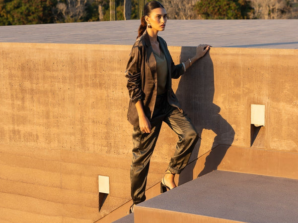 Une femme habillée d'un ensemble tailleur pantalon kaki monte les escaliers extérieurs au coucher du soleil