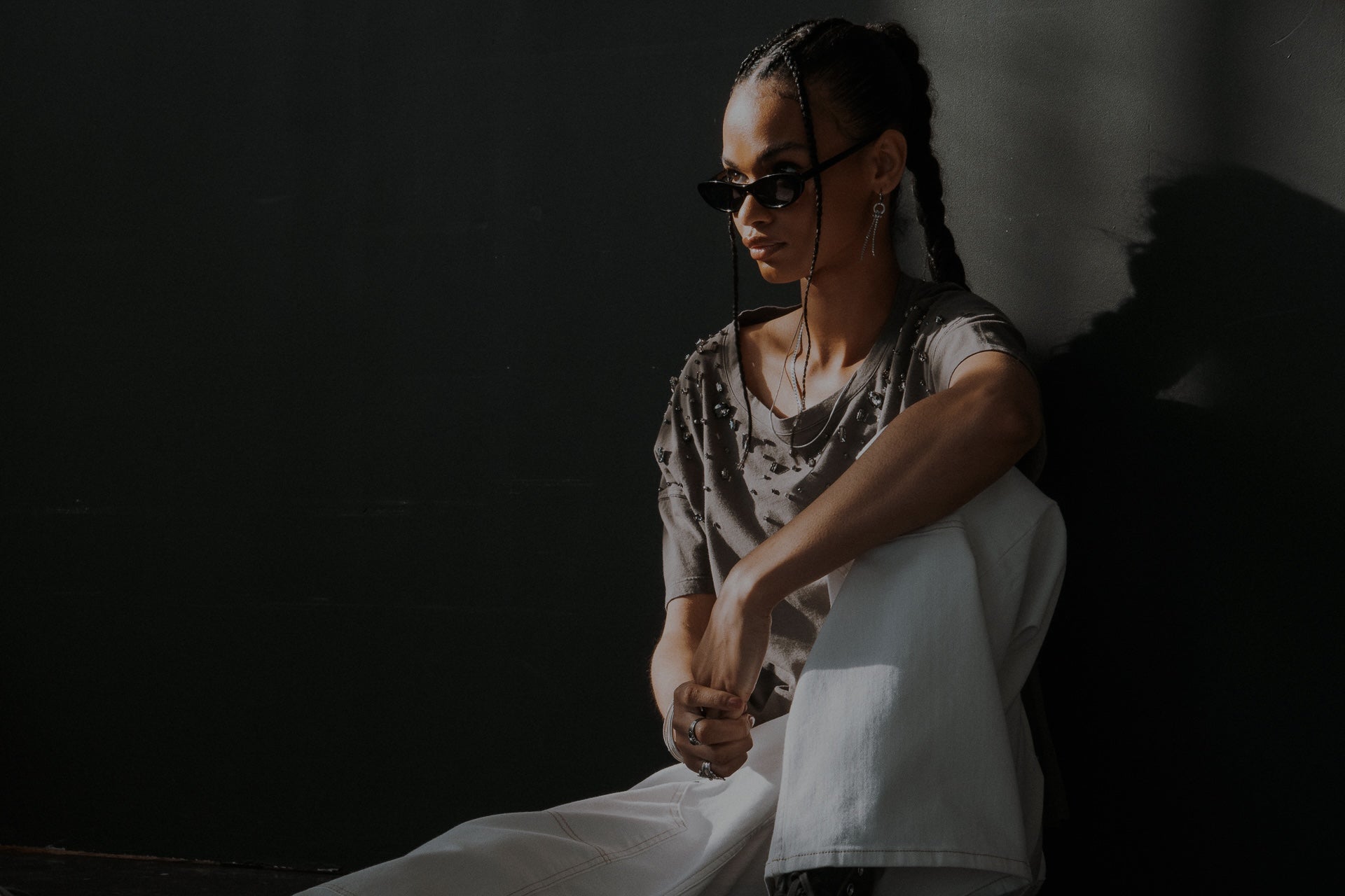 femme assise avec un jean blanc et un tee-shirt gris